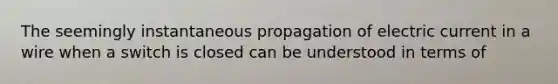 The seemingly instantaneous propagation of electric current in a wire when a switch is closed can be understood in terms of