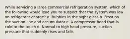 While servicing a large commercial refrigeration system, which of the following would lead you to suspect that the system was low on refrigerant charge? a. Bubbles in the sight glass b. Frost on the suction line and accumulator c. A compressor head that is cold to the touch d. Normal to high head pressure, suction pressure that suddenly rises and falls