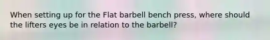 When setting up for the Flat barbell bench press, where should the lifters eyes be in relation to the barbell?