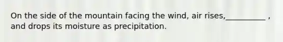 On the side of the mountain facing the wind, air rises,__________ , and drops its moisture as precipitation.