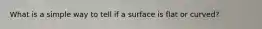 What is a simple way to tell if a surface is flat or curved?