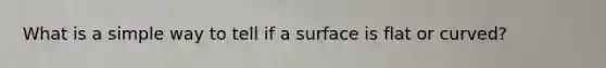 What is a simple way to tell if a surface is flat or curved?