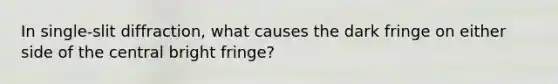 In single-slit diffraction, what causes the dark fringe on either side of the central bright fringe?