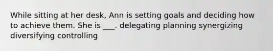 While sitting at her desk, Ann is setting goals and deciding how to achieve them. She is ___. delegating planning synergizing diversifying controlling