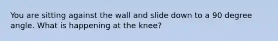 You are sitting against the wall and slide down to a 90 degree angle. What is happening at the knee?