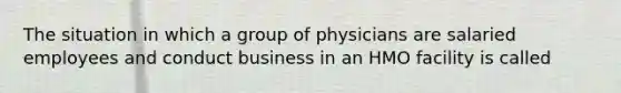 The situation in which a group of physicians are salaried employees and conduct business in an HMO facility is called