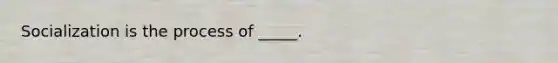 Socialization is the process of _____.