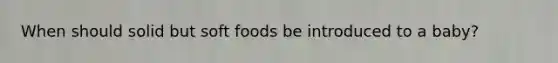 When should solid but soft foods be introduced to a baby?