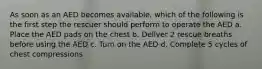 As soon as an AED becomes available, which of the following is the first step the rescuer should perform to operate the AED a. Place the AED pads on the chest b. Deliver 2 rescue breaths before using the AED c. Turn on the AED d. Complete 5 cycles of chest compressions