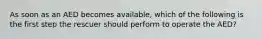 As soon as an AED becomes available, which of the following is the first step the rescuer should perform to operate the AED?