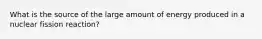 What is the source of the large amount of energy produced in a nuclear fission reaction?