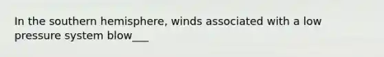 In the southern hemisphere, winds associated with a low pressure system blow___