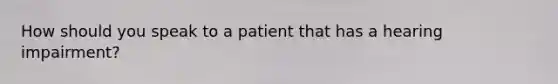 How should you speak to a patient that has a hearing impairment?