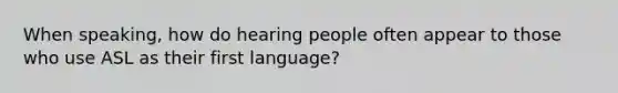 When speaking, how do hearing people often appear to those who use ASL as their first language?