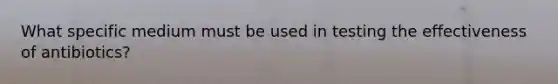 What specific medium must be used in testing the effectiveness of antibiotics?