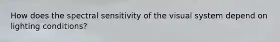 How does the spectral sensitivity of the visual system depend on lighting conditions?