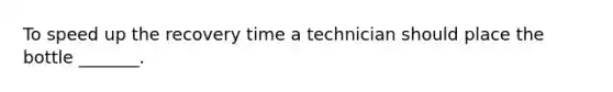 To speed up the recovery time a technician should place the bottle _______.