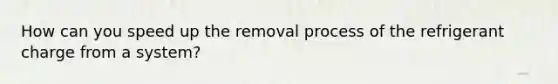 How can you speed up the removal process of the refrigerant charge from a system?