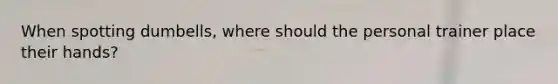 When spotting dumbells, where should the personal trainer place their hands?