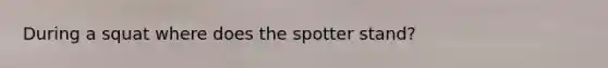 During a squat where does the spotter stand?