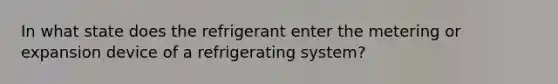 In what state does the refrigerant enter the metering or expansion device of a refrigerating system?