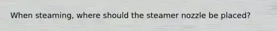 When steaming, where should the steamer nozzle be placed?