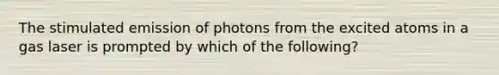 The stimulated emission of photons from the excited atoms in a gas laser is prompted by which of the following?