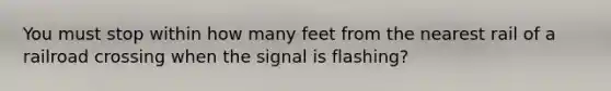 You must stop within how many feet from the nearest rail of a railroad crossing when the signal is flashing?