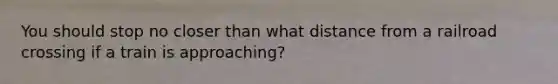 You should stop no closer than what distance from a railroad crossing if a train is approaching?