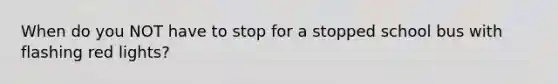 When do you NOT have to stop for a stopped school bus with flashing red lights?