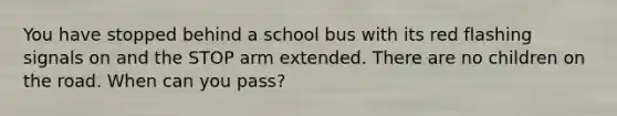 You have stopped behind a school bus with its red flashing signals on and the STOP arm extended. There are no children on the road. When can you pass?