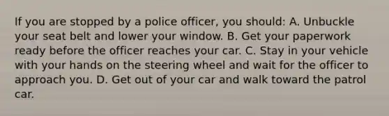 If you are stopped by a police officer, you should: A. Unbuckle your seat belt and lower your window. B. Get your paperwork ready before the officer reaches your car. C. Stay in your vehicle with your hands on the steering wheel and wait for the officer to approach you. D. Get out of your car and walk toward the patrol car.