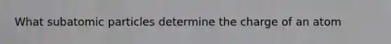 What subatomic particles determine the charge of an atom