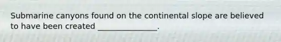 Submarine canyons found on the continental slope are believed to have been created _______________.