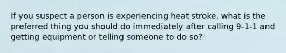 If you suspect a person is experiencing heat stroke, what is the preferred thing you should do immediately after calling 9-1-1 and getting equipment or telling someone to do so?