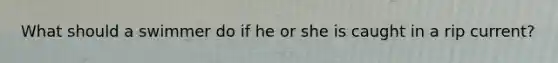 What should a swimmer do if he or she is caught in a rip current?