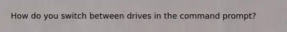 How do you switch between drives in the command prompt?