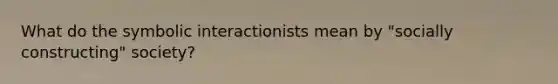 What do the symbolic interactionists mean by "socially constructing" society?