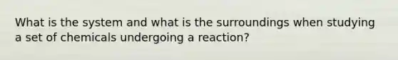 What is the system and what is the surroundings when studying a set of chemicals undergoing a reaction?