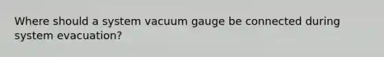 Where should a system vacuum gauge be connected during system evacuation?