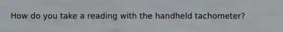 How do you take a reading with the handheld tachometer?