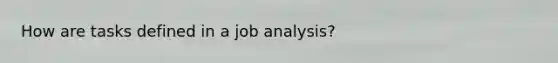 How are tasks defined in a job analysis?