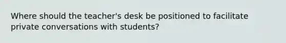 Where should the teacher's desk be positioned to facilitate private conversations with students?