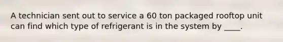 A technician sent out to service a 60 ton packaged rooftop unit can find which type of refrigerant is in the system by ____.