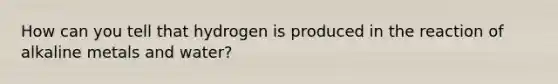 How can you tell that hydrogen is produced in the reaction of alkaline metals and water?