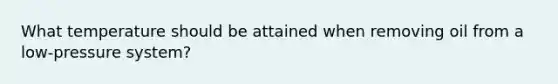 What temperature should be attained when removing oil from a low-pressure system?