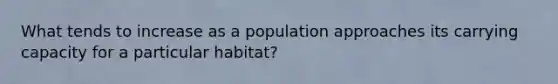 What tends to increase as a population approaches its carrying capacity for a particular habitat?