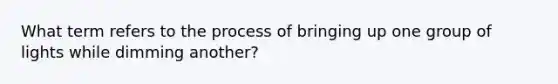 What term refers to the process of bringing up one group of lights while dimming another?