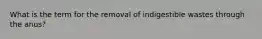 What is the term for the removal of indigestible wastes through the anus?