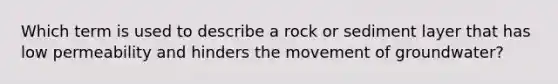 Which term is used to describe a rock or sediment layer that has low permeability and hinders the movement of groundwater?